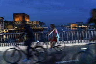 Cyclists on the Inderhavnsbroen cycle and footpath bridge, across the harbour, at night, at Nyhavn,