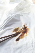 White shirt stained with soy sauce and chopsticks lying on it, no people, close-up, selective focus