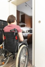 An image of a disabled woman at the open door to the kitchen