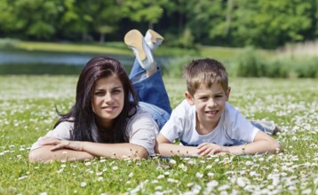 Mother and son lying on the grass in a park in bright sunny day, Belgium, Europe