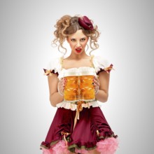 Beautiful Oktoberfest waitress in a traditional Bavarian dirndl holding beer mugs on a grey