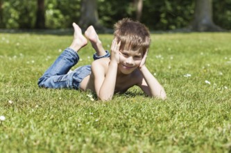 Blond boy lying on grass in a sunny summer day