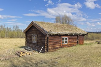 Old timber building at Bjorklund farm museum in spring with clouds in the sky, Svanvik, Norway,