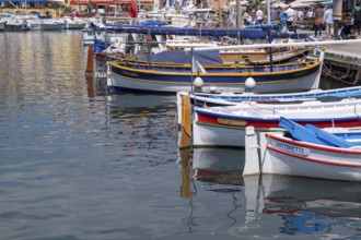 Small colourful boats in the harbour, reflected in the calm water, harbour of Cassis, Provence,