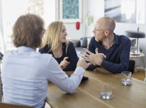 Symbolic photo on the subject of counselling. A young woman and a young man sit together at a table