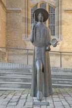 Sculpture Pilgrim with staff and scallop shell and monument to the Way of St James in front of St