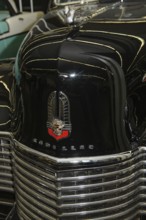 Bonnet with old historic logo underneath radiator grille of vintage classic car historic Cadillac,