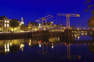 An illuminated canal with bridge and historic buildings in the background at night, evening mood,