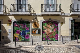 Colorful graffiti art on store shutters enriching the urban street atmosphere, Alfama, Lisbon