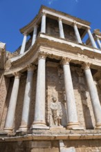 Close-up of a statue in front of ancient columns and stone walls, an example of Roman architecture