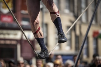 Feet balancing on a tightrope, street artists performing high-wire acrobatics, world's largest