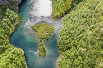 Aerial view of an island in a turquoise colored river surrounded by birch forest, valley