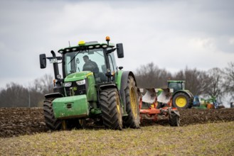 Tractor with a plough preparing the soil of a field for planting, Agriculture, Spring