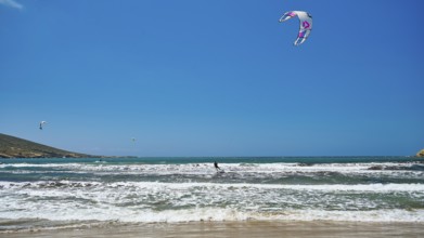 Kitesurfer on wavy sea under blue sky with kite, surfer's paradise, kitesurfer, windsurfer,