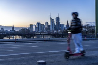 Skyline of the city centre of Frankfurt am Main, e-scooter on the raft bridge, dusk, river Main,