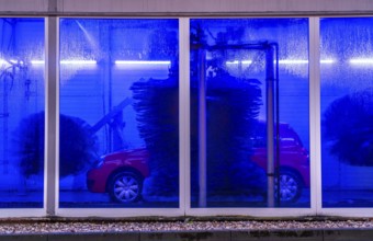 Car in an automatic car wash, car wash tunnel, cleaning foam is sprayed on, rotating brushes clean