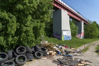 Illegally disposed waste, car tyres, building rubble, household waste, clothing, on a path next to