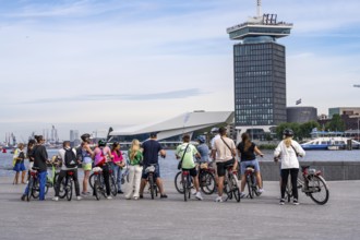 Sightseeing by bike, guided bike tour, here at the river Ij, view of A'DAM Lookout, building with