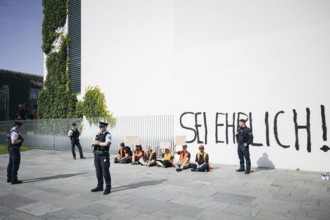 Demonstrators sit with signs in front of the Federal Chancellery, the demonstrators have written