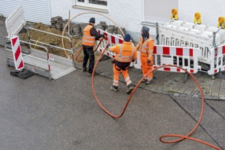 Construction workers laying fibre optic cable, cable trench, construction site, fibre optic