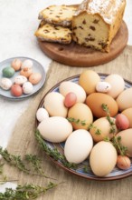 Homemade easter colored eggs on plate and raisins cake on a gray concrete background and linen