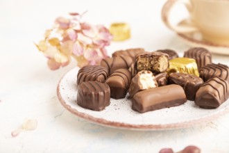 Chocolate candies with cup of coffee and hydrangea flowers on a white concrete background. side