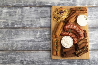 Set of snacks: sausages, nuggets, cheese sticks, toast, cabbage salad on a cutting board on a gray