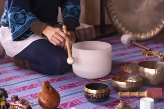 Close-up of a woman's hands playing a quartz singing bowl, while guiding a sound meditation