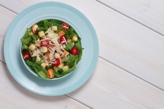 Classic Caesar salad, with cherry and croutons, top view, on a white table, horizontal, no people