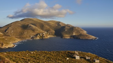 View of a sunlit island in the Mediterranean Sea with green hills and late sky light, southern tip,