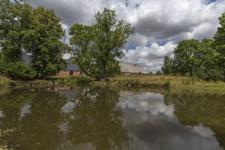 Former horse stable and barn from 1920, in front the extinguishing pond on an estate, Othenstorf,