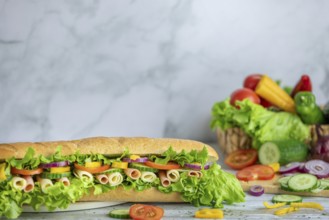 A long sandwich with a rich topping of vegetables, sausage and cheese, tomatoes, peppers, lettuce