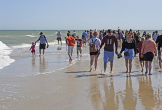 Ttourists standing at the northern tip of Denmark where the Baltic Sea and North Sea meet at Skagen