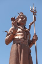 Photo from street level upward view of larger-than-life figure of god deity of Hindi Hindu statue