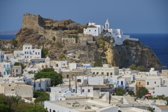 White painted houses and an old castle on a hill overlooking the blue ocean on a clear day, morning