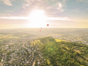 Hot air balloons flying over a town and wooded hills at sunset, Calw, Black Forest, Germany, Europe