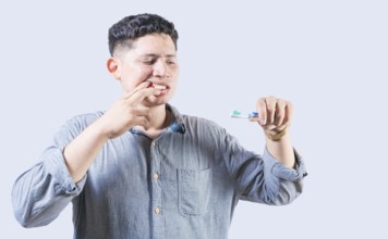 Man suffering from gum pain holding toothbrush. People holding toothbrush with gum problem. Person