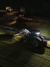 Tractor with front loader working at night on a rural field, maize harvest, Dachtel, Black Forest,