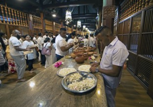 Sri Lankan pilgrims offering white jasmine flowers at the Buddhist Temple of the Tooth or Sri