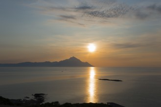 The sun rises, illuminating the sea and an island in the distance, view of Mount Athos, Orthodox