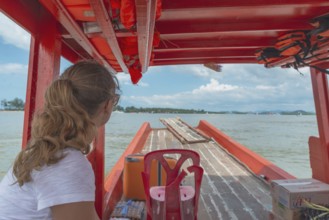 A woman on a small red ferry in Thailand, view of the Adaman Sea