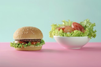 Comparison of healthy and unhealthy food with hamburger on one side and bowl with salad on other