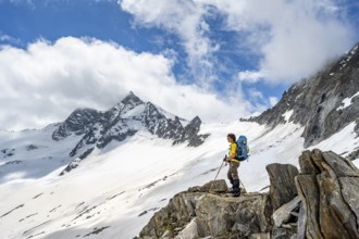 Mountaineer on a rock between snow, descent from the summit of Schönbichler Horn, view of