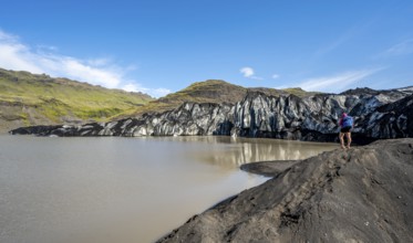 Tourist on the shore of a glacier lagoon, glacier tongue and lake, Sólheimajökull, South Iceland,