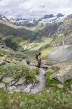 Mountaineer on a hiking trail in front of a picturesque mountain landscape, rocky mountain peaks