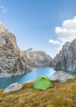 Green tent at the turquoise mountain lake Kol Suu with rocky steep mountains, Kol Suu Lake, Sary