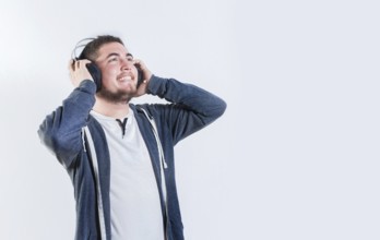 Guy enjoying music holding headphones isolated. Happy person listening to music holding headphone