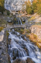 Impressive waterfall flowing over a rocky stream under a bridge, St. Beatus Caves, Switzerland,