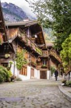 Person walking through a picturesque old street with half-timbered houses in autumn, Lake Brienz,