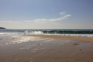 Breaking waves on a calm stretch of beach under a clear sky, Tarifa